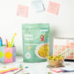 Millet Pasta package on a desk with a bowl of pasta and stationery items.